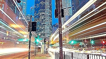 A city scape at night with trailing lights from cars going by.