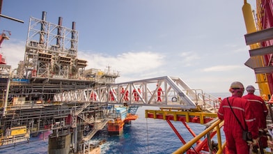 Рабочие переправляются на новую платформу, построенную рядом с существующим глубоководным проектом «Малампая»