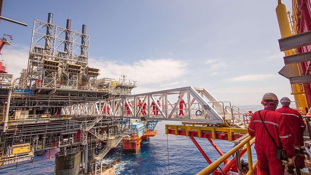 Рабочие переправляются на новую платформу, построенную рядом с существующим глубоководным проектом «Малампая»