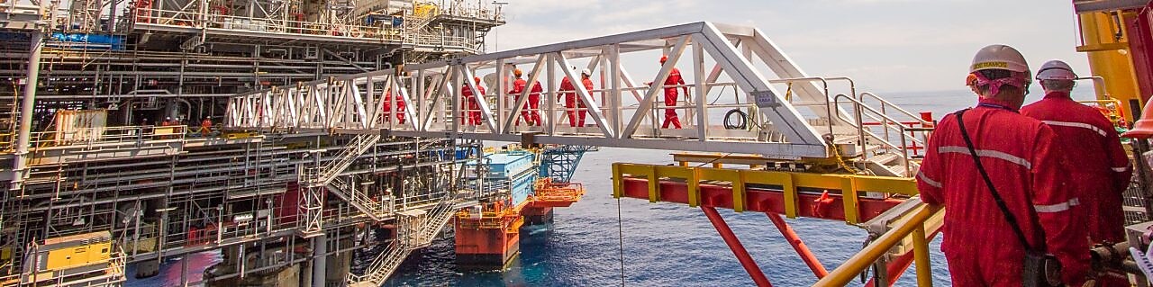 Рабочие переправляются на новую платформу, построенную рядом с существующим глубоководным проектом «Малампая»