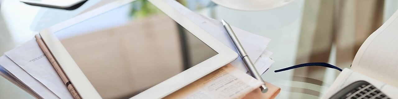 Tablet computer, newspaper, coffee cup and cell phone on desk