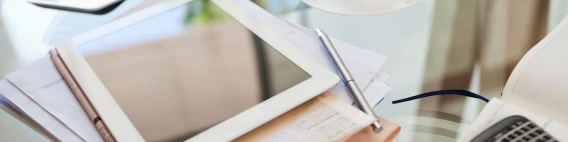 Tablet computer, newspaper, coffee cup and cell phone on desk