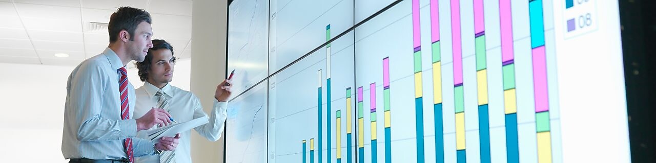 Бизнесмены анализируют данные отчетности, показанные на большом цифровом экране
