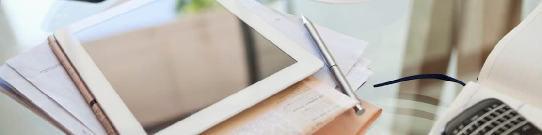 Tablet computer, newspaper, coffee cup and cell phone on desk