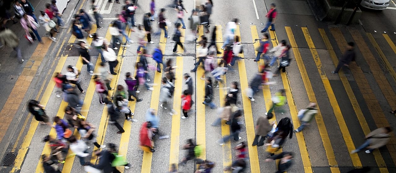 Пешеходы переходят оживленную улицу в Гонконге